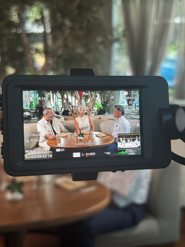 A camera viewfinder framing an on-location interview, earned media in production.
